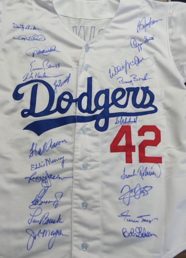This home white Dodgers #42 Robinson jersey is in NM condition, and comes trimmed in red and blue, with everything sewn.  It is front-signed in blue sharpie by 21 different all time great black players, including Jeter, Banks, Henderson, Aaron, Murray, Jackson, Griffey Jr, Brock, Morgan, Mays, Gibson, Robinson, Bonds, McCovey and many more.  With several now deceased, and so many enshrined in Cooperstown, retail is well into the thousands!