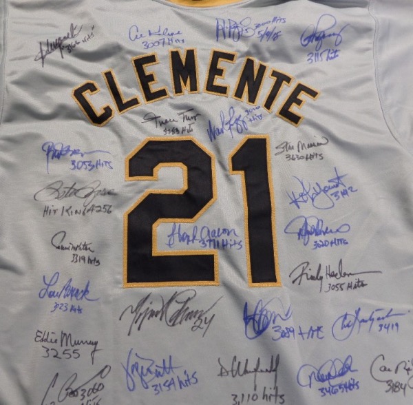 This awesome piece is a road gray #21 Clemente Pittsburgh Pirates 2XL custom throwback jersey, hand-signed in blue and black on the back by no less than 24 members of the famed 3000 Hit Club.  Included are Mays, Boggs, Pujols, Brett, Musial, Yount, Henderson, Jeter, Yaz, Ripken, Winfled, Biggio, Murray, Brock, Molitor, Rose, Aaron, and more.  Really a fantastic jersey, and with so many all time greats present, and a few now deceased, retail is well into the thousands!