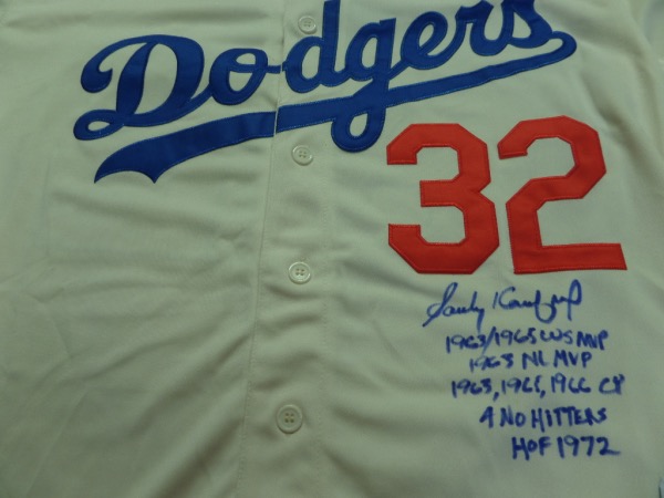 This size L home white 1955 Brooklyn Dodgers throwback jersey from Mitchell & Ness is trimmed in red and blue with everything sewn on, and comes front signed in blue sharpie by the great 3 time Cy Young Award Winner and HOF lefty!  The signature grades a legible 8.5, includes 4 No Hitters, 63'65'66 Cy, HOF 1972, 63/65 WS MVP and 63 NL MVP inscriptions, and will show off brilliantly in any baseball collection!