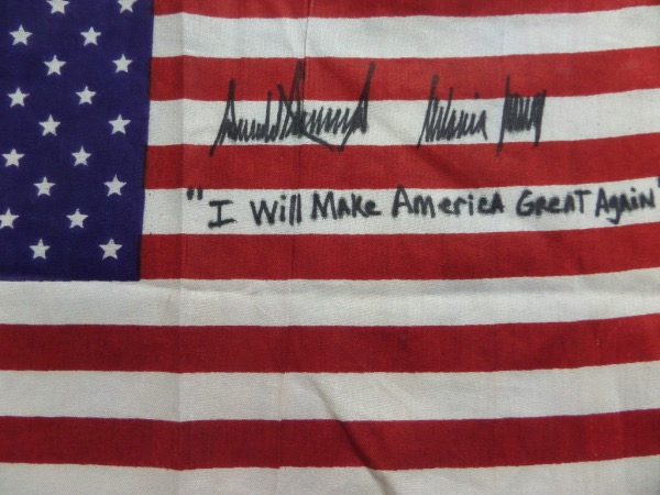 This vintage US flag measures approximately 8x12, is in NM condition, and comes black sharpie signed by the POTUS and his First lady wife. Both signatures are stellar, grading 9's, and with a "I Will Make America Great Again" slogan written in his hand as a bonus, retail is high hundreds to low thousands!