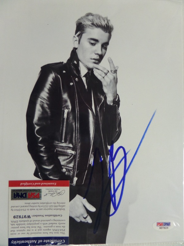 This black and white 8.5x11 photo is a black and white image of Justin Bieber all grown up, and posing in a leather jacket.  It is hand-signed in blue sharpie by the pop star himself, grading an overall 7, and including a COA from PSA/DNA (W97829) for authenticity.  Valued well into the hundreds!