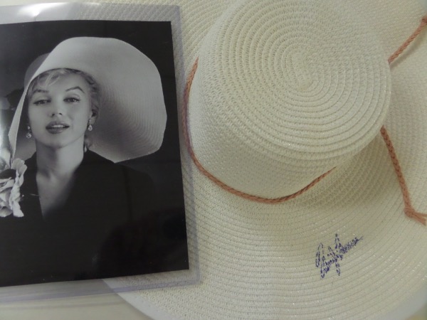 This unbelievable opportunity is an absolute MUST for silver screen collectors and dealers alike.  It is a very large white ladies' hat, in fabulous condition, and measuring right around a foot and a half in diameter, with a pinkish string attached.  It is hand-signed in blue ink by the icon of icons herself, grading a tough but still legible 5, and the lot also includes a black and white 8x10 of Marilyn, and she looks to be wearing this exact hat in the picture.  Talk about a centerpiece for any Marilyn Monroe tribute!