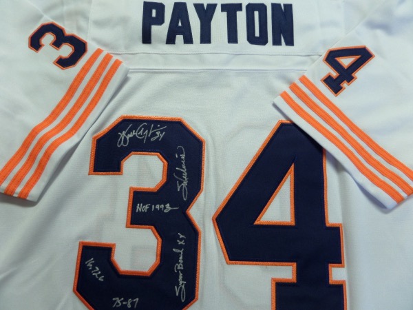 This white size 50 Chicago Bears #34 Payton throwback jersey is a 1985 throwback from Mitchell & Ness, and is in NM/MT condition, with everything sewn in navy blue and orange.  It comes silver sharpie-signed on the back number by the former rushing king himself.  The signature grades a legible 8, and includes HOF 1993, 16,726, 34, Sweetness, Super Bowl XX, and 75-87.  AWESOME NFL and Bears item, and with his death now over 20 years ago, retail is low thousands!