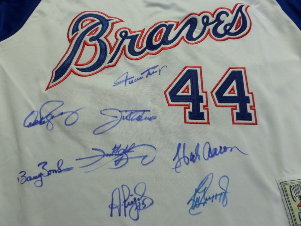 This blue #44 Hank Aaron 1974 throwback Braves jersey from Mitchell & Ness is in NM/MT condition, a size L, with everything sewn.  It is hand-signed on the front in blue and black by 8 of the 9 members of the RARE 600 Home Run Club, including Aaron, Griffey Jr, Thome, Mays, Sosa, Bonds, Pujols and ARod.  Awesome looking jersey, a MUST for framing and display, and retail is thousands!