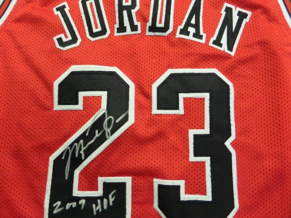 This mint Chicago road red is trimmed in team white and black colors, has sewn on everything as well as name on back, and comes back #23 IN PERSON signed by the greatest ever. It grades a 10 in bold clean silver paint pen, has his HOF Induction date written as a bonus, and value with Lee's added ok for authenticity is thousands. 