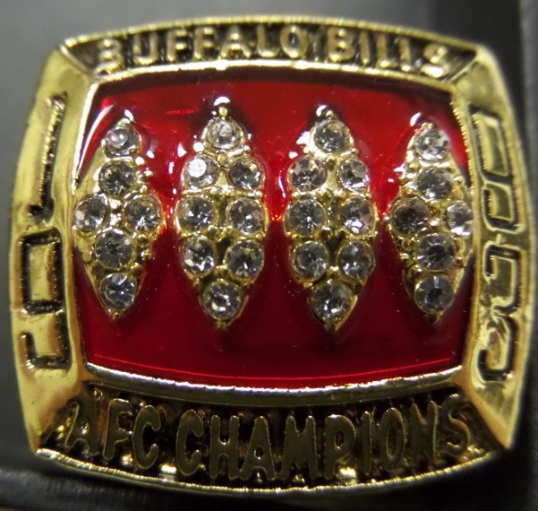 This RARE ring is custom made to look exactly like the AFC Championship ring that JIM KELLY got in 1993, with CZ Diamonds all over the ring. The top has a Red Stone background, with 4 LARGE CZ's in the shape of footballs, "1993" on each side of stones, and "BUFFALO BILLS" across top, and "AFC CHampions" across the bottom. One Shank has "KELLY" with Bills Helmet and 14--5. The other shank has tons of engraving with the 4 Super Bowls they were in from 2008--2012. This is a gorgeous ring, size 11, This is a true beauty and a must for any Bills fans, and well valued