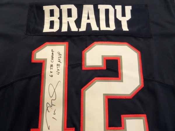 This fantastic blue size L New England Patriots #12 Brady jersey from Nike is still tagged as new, and comes with everything sewn.  It is back number-signed in black sharpie by the future HOF passer himself, grading a legible 8-8.5, and including super cool 6X SB CHAMP and 4X SB MVP inscriptions, and will really show off spectacularly when framed for display!  Valued into the very high hundreds!
