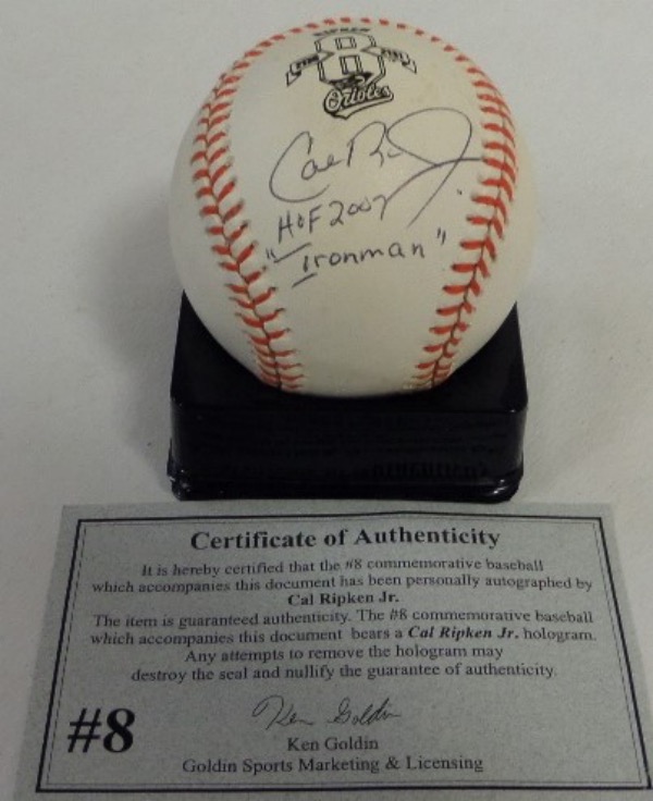 This orange-laced commemorative Cal Ripken 2131 Official AL baseball from Rawlings is in EX/MT to NM condition, and comes black ink-signed on a side panel by the Ironman himself!  the signature grades an overall 8.5, complete with HOF 2007 and "Ironman" inscriptions, and the ball comes with a COA and hologram from Ken Golden himself for rock solid authenticity!