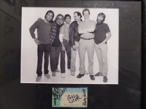 This 12x15 framed display is in VG/VG+ shape, featuring a black and white photo of the band in the early 1980's.  Under the photo is an original 1992 Dead concert ticket, hand-signed in black sharpie by 4 band members.  Included are Jerry Garcia, Bob Weir, Mickey Hart and Bill Kreutzman, and this frame-ready display is valued into the thousands, especially with the Deadheads!