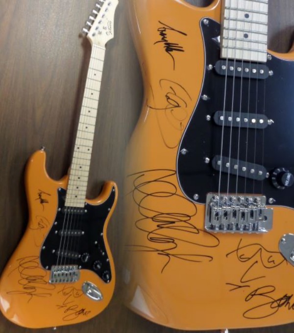 This STUNNING mint burnt orange electric beauty comes in box with original carry bag, straps,etc.  It comes signed perfectly in black by ALL 4 guys with a great personal portrait of his face by Bono.  Also included are Adam Clayton, Larry Mullen Jr. & the Edge.  Guaranteed authentic and retails into the thousands easily.