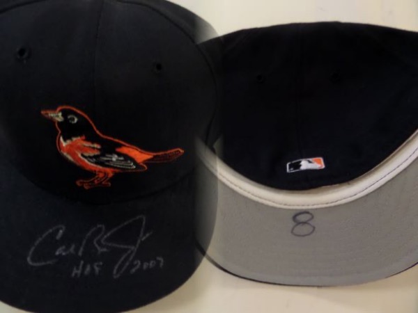 This 7 3/8 fitted black Baltimore Orioles cap looks to have been worn in actual MLB action by HOF O's shortstop/3b, Cal Ripken Jr.  It has his number 8 penned in black sharpie on the bill's underside, and is hand-signed on the top of the bill in silver sharpie by the Iron Man himself, grading a 7, with HOF 2007 added in his hand.  A gorgeous piece, and retail is low thousands!