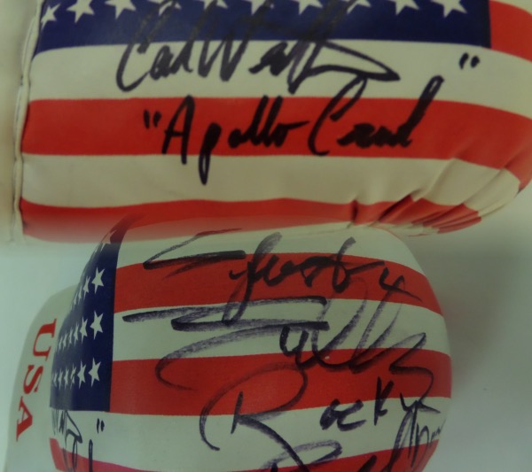 This mint lace-up  ounce 16 ounce glove has the US flag on it and comes signed GORGEOUSLY by both of these ROCKY superstars in black sharpie with Sly including "Rocky Balboa" & Carl including "Apollo Creed" with their autographs! Ideal display glove and guaranteed authentic. Retails in the high hundreds+. Rare.