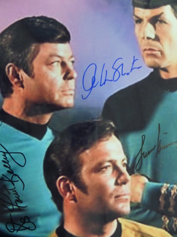 This rare color 8x10 image shows William Shatner, DeForrest Kelley and Leonard Nimoy from the 1960's hit sci-fi TV show, and comes black and blue sharpie signed by all 3 space legends. It grades a clean bold 10 all over, shows off easy from 16 feet away, and value with the added SCM lifetime COA is about a grand. 