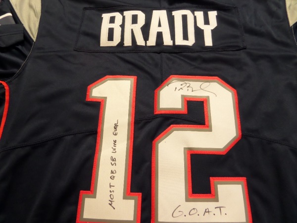 This fantastic blue size L New England Patriots #12 Brady jersey from Nike is still tagged as new, and comes with everything sewn.  It is back number-signed in black sharpie by the future HOF passer himself, grading a legible 8-8.5, and including super cool MOST QB SB WINS EVER and G.O.A.T. inscriptions, and will really show off spectacularly when framed for display!  Valued into the very high hundreds!