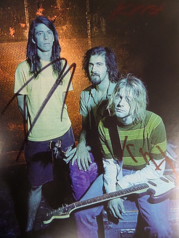 This full color 8.5x11 photo shows all three members of Nirvana in the early 1990's.  It is hand-signed in black sharpie by all three, including Krist Novelesic, Dave Grohl, and Kurt Cobain, and with Cobain's tragic death now nearly 3 decades ago, retail here is well into the hundreds!