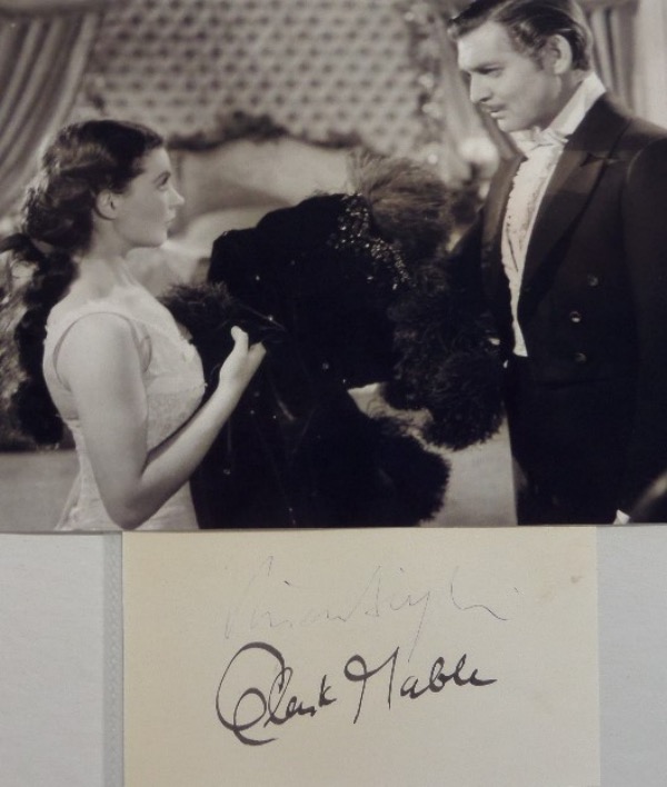 This fantastic Hollywood collectors item is a vintage cut of white paper, measuring a sizeable 2.75x4.75, in NM condition, and hand-signed by the screen duo of Clark Gable and Vivien Leigh.  Gable's brown fountain pen ink signature grades a strong 7, and Leigh's blue ink signature grades about a 4, and the cuts come with a black and white "Gone With The Wind" photo for display!