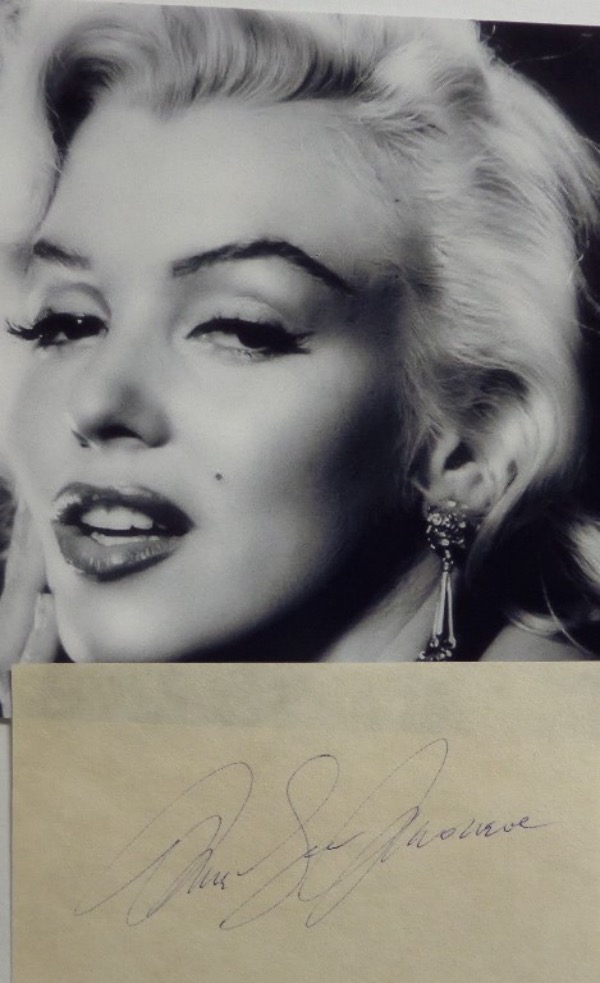 This vintage cut of white paper measures approximately 3x5, and comes hand-signed in blue ink by Hollywood GIANT, Marilyn Monroe.  This is an aged and lighter signature, grading about a 5 overall, and the cut is accompanied by a B&W photo of Marilyn!  WOW!!!