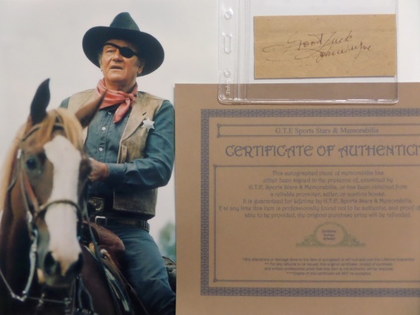 This vintage cut of light brown paper measures about 2x4.5, and comes hand-signed in fountain pen ink that now appears dark red by film icon, John Wayne.  The signature grades a legible 6, with Good Luck added, comes with a COA from GTE Sports Stars & Memorabilia, and includes a color "True Grit" photo for display.  Valued into the mid hundreds!