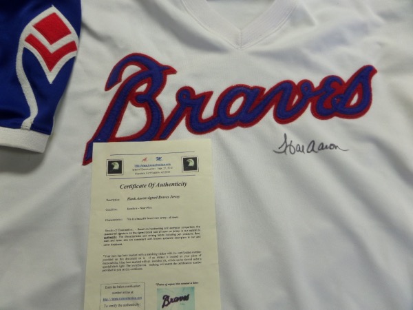 This Braves mint home white is trimmed in red and blue team colors and comes boldly black sharpie signed by the REAL All-Time "HR King" across the front. It grades a clean bold 10 all over, shows off EZ from 20 feet away, and has a lifetime LOA intact from Icon Authentics for certainty. 