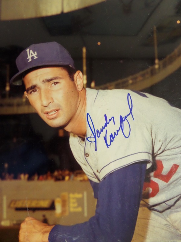 This full color 8x10 photo shows Koufax in a "follow through" pitching pose, wearing his road Dodgers grays.  It is hand-signed boldly in blue sharpie by the 3 time Cy Young Award winner and HOF Dodgers ace himself, and is MINT, and a perfect size for framing and display.  Valued well into the hundreds from this hard to get to HOF great!