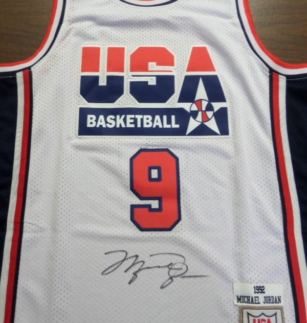 This 1992 model white USA Basketball "Dream Team" #9 Jordan jersey is from Mitchell & Ness, a size 50 with original tagging attached.  It is front-signed in black sharpie by His Airness himself, his HUGE signature grading a strong, clean and legible 8.5.  A great looking jersey, a MUST for any basketball collection, and retail is very high hundreds!