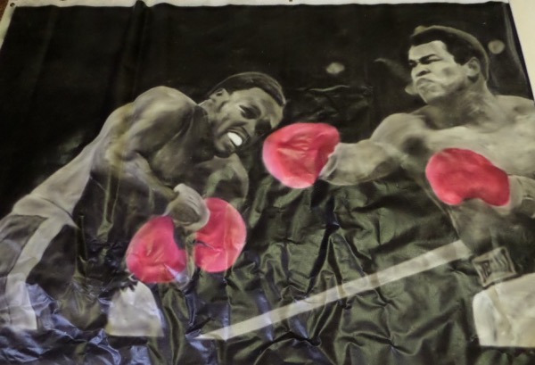 This original oil painting is 6x8 FEET in size, done on real artists canvas, and shows Ali blasting Frazier with a right hand during their classic 1975 third Heavyweight title fight in Manila. The artists is Joe Blah and he painted it out of world famous JB Studios. It hung for years over a boxing ring where boxers and MMA Fighters would train for Bellator. Unreal item, and a rare one of a kind worth thousands.  