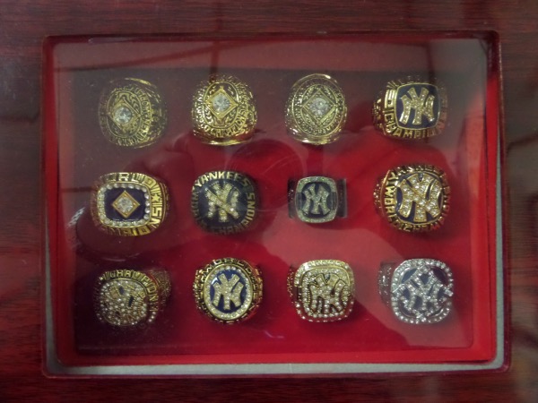 This one of a kind opportunity is taylor-made for all you ring collectors out there--especially the Yankees fans!  Here we have a wooden ring display box in VG+ condition, with settings for twelve rings, and we've even got all twelve rings to fill it!  Included are NM/MT replica championship rings from 1950, 1951, 1952, 1977, 1978, 1996, 1998, 1999, 2000 and 2009, with a couple of different models included for various years.  Check out our attached photo to see this beautiful display, and retail is easily high hundreds and beyond!