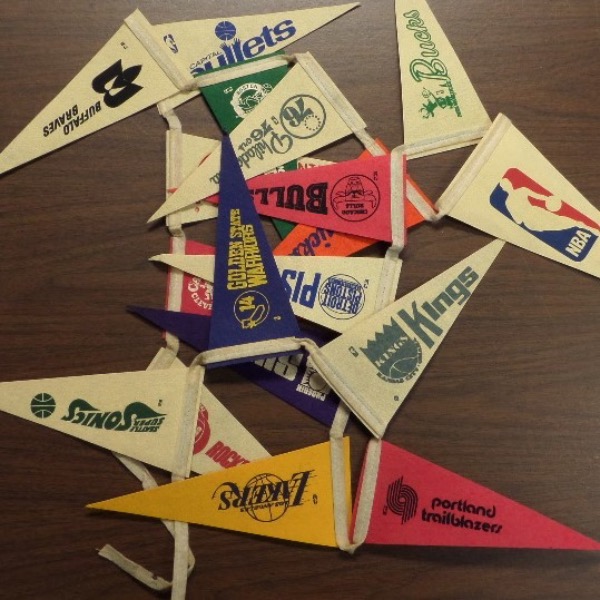 This vintage lot is so rare, you can't even find it on EBay ... but guess what?  You can, will, and do NOW find it here!!!  This is a collection of 10" mini NBA team logo pennants, all strung together to make a banner that was most likely used at a sports bar.  It is completely intact and in EX/MT condition, featuring all of the NBA teams at the time, like the Lakers, 76'ers, Celtics, Bucks, Suns, Knicks, etc., even the Capital Bullets and Baltimore Braves.  A MUST for the vintage NBA collector, and retail, if you can find another, is mid hundreds at least!