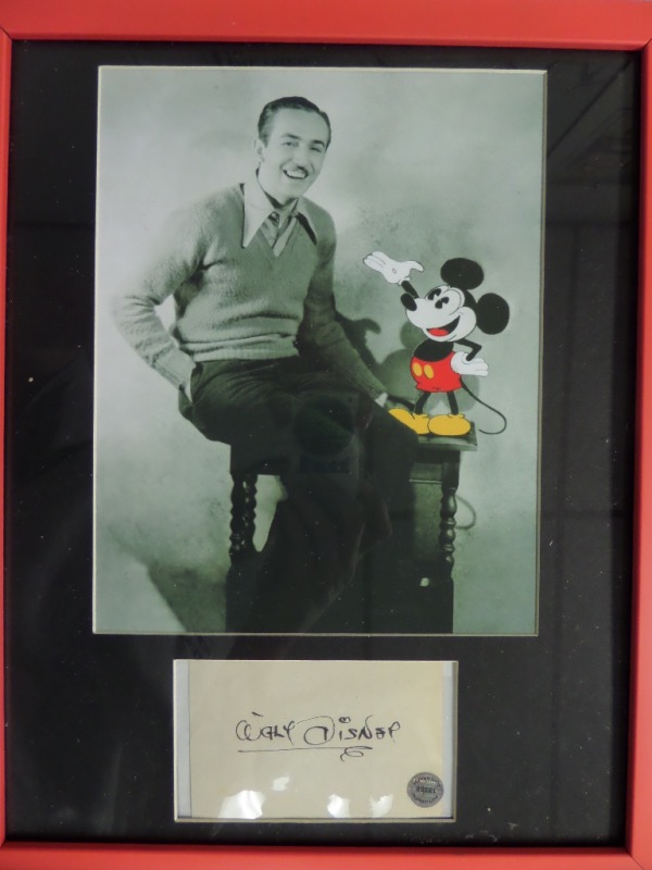 This black matted display is framed in bright red, measures near 12x16 in size, and has TWO custom cutouts pertaining to the late Genius. I see a B&W 8x10 with him and Mickey Mouse together, but the main piece here is a hand signed 1960's Government postcard matted below. Signed in bold black ink, certified by SCM, and value is sky high. 