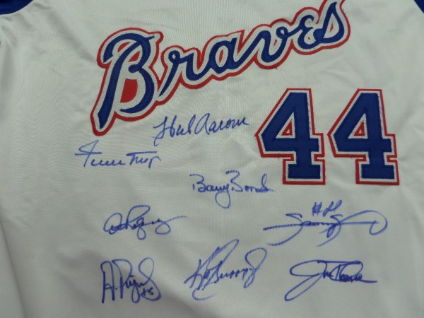 This blue #44 Hank Aaron 1974 throwback Braves jersey from Mitchell & Ness is in NM/MT condition, a size L, with everything sewn.  It is hand-signed on the front in blue sharpie by 8 of the 9 members of the RARE 600 Home Run Club, including Aaron, Griffey Jr, Thome, Mays, Sosa, Bonds, Pujols and ARod.  Awesome looking jersey, a MUST for framing and display, and retail is thousands!