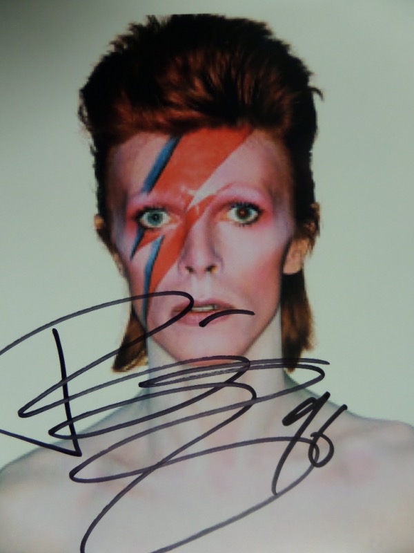 This full color 8.5x11 photo shows the 1970's-80's popular music star in full makeup and staring at the camera.  It is hand-signed in black sharpie by Bowie himself, grading a clean 9 overall, and with his untimely death now 7 years ago, retail is easily mid/high hundreds on this one!