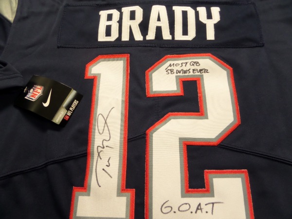 This fantastic blue size L New England Patriots #12 Brady jersey from Nike is still tagged as new, and comes with everything sewn.  It is back number-signed in black sharpie by the future HOF passer himself, grading a legible 8-8.5, and including G.O.A.T. AND most QB SB WINS EVER inscriptions, and will really show off spectacularly when framed for display!  Valued into the very high hundreds!