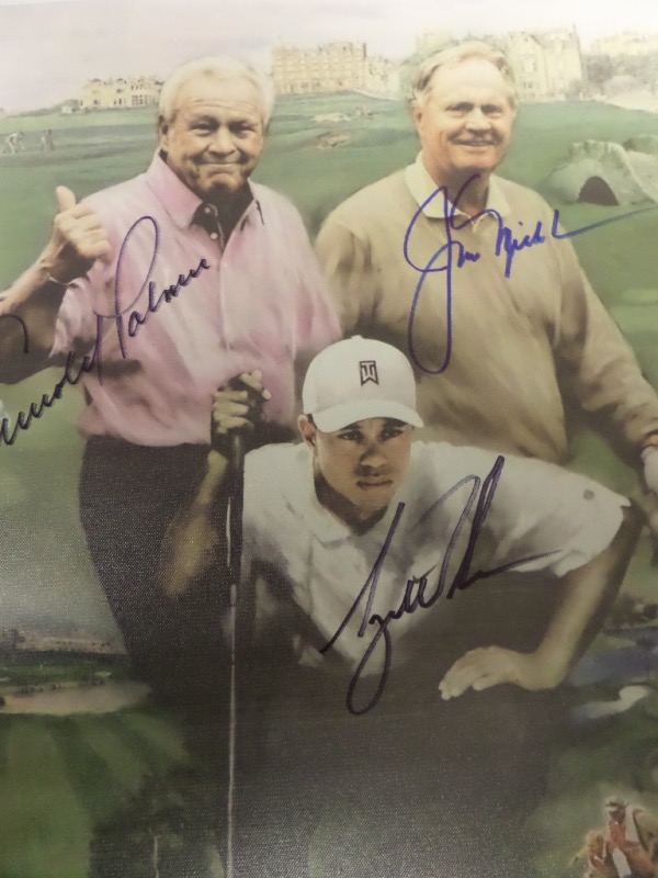 This 18x22" artist's litho print is done on canvas and in NM condition.  It is a full color image of three golf greats, with the Ancient Golf Club at St. Andrews in the background, and comes hand-signed by three of the greatest golfers of all time, including Tiger Woods, Arnold Palmer, and the greatest of them all, the one and only Golden Bear, Jack Nicklaus!  Valued into the low thousands!