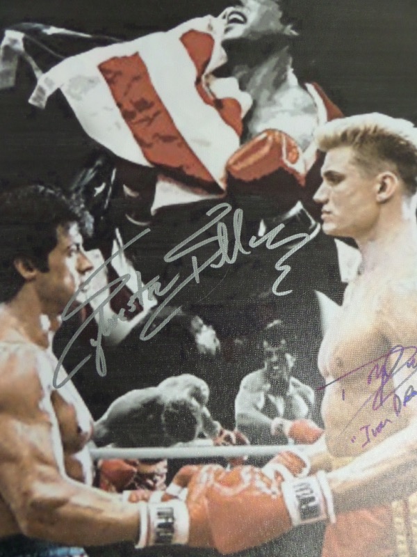 This 18x22 litho print is done on canvas, with a collage of images from the hit 1985 sequel, "Rocky IV."  It is hand-signed in silver by Sylvester Stallone, and in blue sharpie by Lundgren, who has added an Ivan Drago inscription.  AWESOME piece, and an absolute must for fanatics of the franchise!