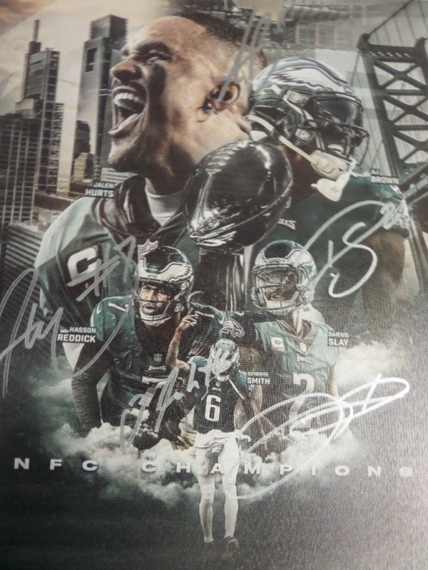 This full color Philadelphia Eagles 2022 NFC Champions litho print is done on an 18x22 canvas, and shows five key members of last year's successful football team.  It is hand-signed in silver by all five, including QB Jalen Hurts, WR's AJ Brown and Davonta Smith, and defensive All Pro's Hasson Reddick and Darius Slay.  AWESOME Eagles item, and we look forward to the Eagles fans' Battle Royale that will ensue to see who gets it!