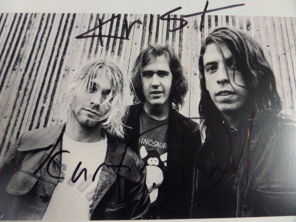 This black and white 8.5x11 photo shows all three members of supergroup Nirvana in the early 1990's.  It is hand-signed in black sharpie by all three members, including 2 time HOF'er Dave Grohl, Krist Novelesic, and long-deceased frontman and songwriter, Kurt Cobain.  Ready for framing and display, and retail is high hundreds with Cobain's murder now a full 3 decades ago!