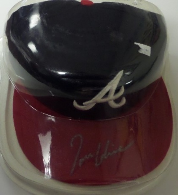 This fitted 7 1/2 Atlanta Braves pro style cap from New Era is still in store-bought condition, and comes hand-signed in silver against the red brim by HOF lefty, Tom Glavine.  The signature grades an overall 8-8.5, and the cap is affixed with a hologram on the underside from Fleer (1637026) for rock solid authenticity.  A MUST for any Bravos fan or MLB HOF collector, and retail is mid hundreds!