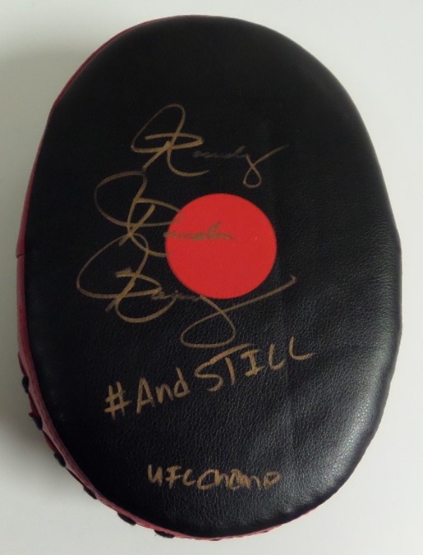 This new hand/fist strike bag is red and black, comes gold paint pen signed by the ultra tough signer, and grades as good as it gets. She has added "And Still UFC Champion" as a bonus, and value is middle hundreds on the classy fight item. 