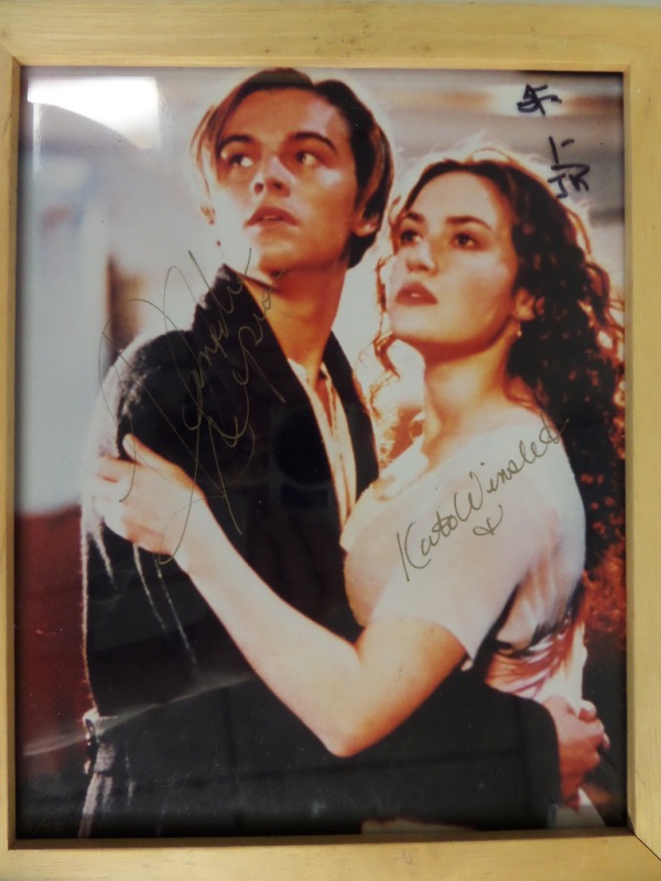 This wood-framed color 8x10 shows the two stars from the blockbuster 1997 film, "Titanic," Kate Winslet and Leonardo DiCaprio, in an embrace, while looking at their impending doom!  It is hand-signed in GOLD paint pen by both mega stars, and this display-ready silver screen gem is valued into the mid hundreds!