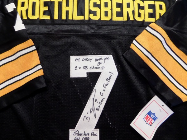 This black size 50 Steelers throwback from Mitchell & Ness is still tagged as new, and comes with everything professionally-stitched.  It is back number-signed in black sharpie by the future HOF passer himself, grading a legible 8.5, with Big Ben, 6X Pro Bowl, Steelers Rc 64,088 418 TD's, 04 OROY, Here We Go! and 2X SB Champ inscriptions.  WOW!  That's a ton!  Guy probably got writer's cramp on this baby!  Valued into the high hundreds!