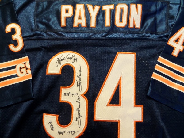 This navy blue size 50 Chicago Bears #34 Payton jersey is a 1985 throwback from Mitchell & Ness, and is in NM/MT condition, with everything sewn in white and orange.  It comes black sharpie-signed on the back number by the former rushing king himself.  The signature grades a legible 8, and includes HOF 1993, 16,726, MVP 1977, 34, Sweetness, and Super Bowl XX.  AWESOME NFL and Bears item, and with his death now a quarter of a century ago, retail is low thousands!