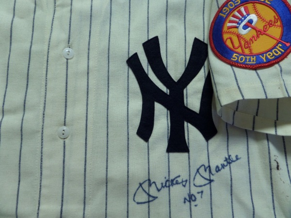 This home white, pinstriped #7 New York Yankees throwback is an XL from Mitchell & Ness, and comes to us in NM condition, with everything sewn, including a 1952 NY Yankees 50th Year patch on the left arm.  It is front-signed in blue sharpie by The Mick himself, HOF'er and all time great Mickey Mantle, and grades a strong, clean 8.5, with No. 7 added as an inscription.  A beautiful display jersey, valued into the low thousands!!!