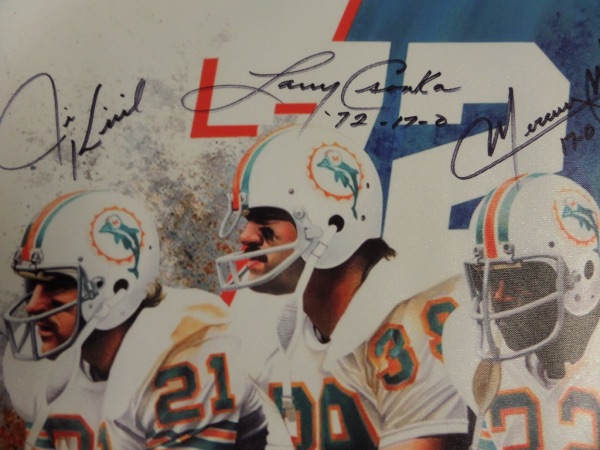 Commemorate the season of perfection with this full color 18x22 canvas litho print, featuring a color image of the three dominant Dolphins running backs that helped bring the only perfect season in NFL history.  It is hand-signed in black sharpie by all three, including Mercury Morris, Jim Kiick, and HOF great, Larry Csonka.  Valued into the very high hundreds!