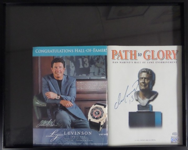 This 17x21 black-framed display houses a "Path to Glory" Dan Marino Hall of Fame Enshrinement program in NM condition, and hand-signed in blue felt tip marker by the record-smashing HOF QB himself.  This signature grades a strong 8.5 at least, and the program is affixed not only with Marino's own hologram, but also one from Mounted Memories for rock solid authenticity!  Ready for display, and valued well into the hundreds!
