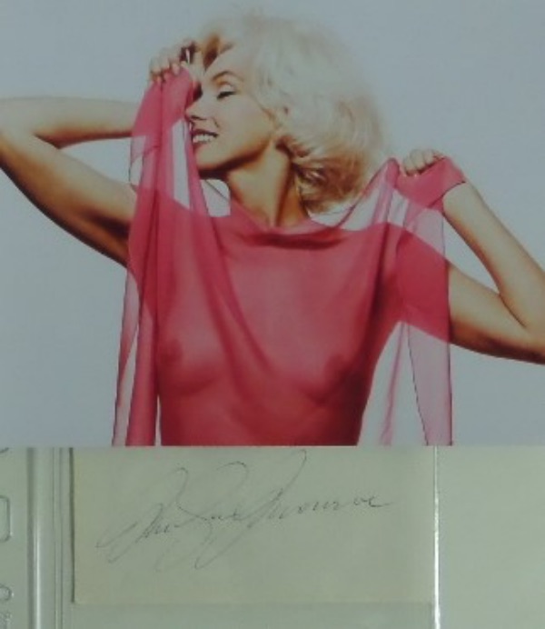This vintage cut of white paper measures approximately 2.25x4.75, and comes hand-signed in black ink by Hollywood GIANT, Marilyn Monroe.  This is an aged and lighter signature, grading about a 5-5.5 overall, and the cut is accompanied by a SEXY "see through top" color photo of Marilyn!  WOW!!!