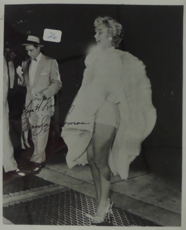 This amazing Hollywood collector's item is a black and white 8x10 that shows Marilyn Monroe holding down her dress as it is being blow up by the subway below.  This is, I think, a reproduction of the original "Seven Year Itch" scene, as Frank Sinatra is seen in the background, and I'm pretty sure he was not in that movie, but WOW, what an image either way, and this one comes hand-signed in black by Marilyn, with her standard Love & Kisses inscription added.  The signature grades a strong 8 at least, and, with Marilyn's tragic death now over 60 years ago, retail is WELL into the thousands!